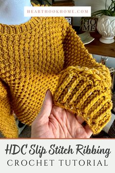 a hand holding up a yellow knitted sweater with the words, hdc slip stitch rib