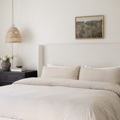 a bed with white sheets and pillows in a bedroom