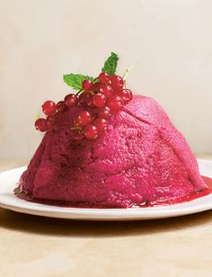 a red cake on a white plate topped with berries