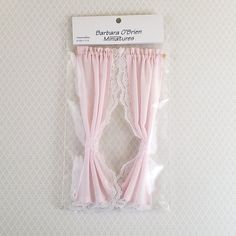 two pink curtains with lace on them are in a package for the doll's room