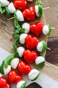 several red and white peppers on skewers with basil sprinkled on them