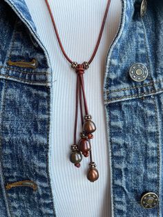 a close up of a person wearing a blue jean jacket and necklace with pearls on it