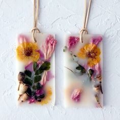 two square glass pendants with dried flowers on them