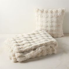 two white pillows sitting next to each other on top of a bed covered in fur