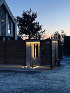 the entrance to a modern home with an illuminated sign on it's wall and gate