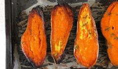 four cooked sweet potatoes sitting on top of a baking sheet with herbs sprinkled on them