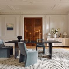 a living room with two chairs and a table in front of a door that has candles on it