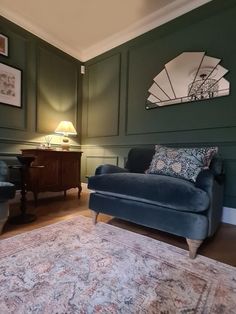 a living room with two chairs and a rug in front of the couch is painted green