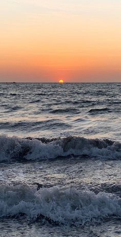 the sun is setting over the ocean waves