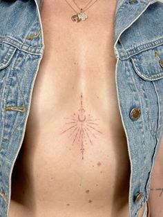 a woman's chest with an arrow tattoo on her left side and sunbursts in the middle