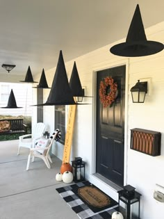 the front porch is decorated for halloween with black and white decorations, pumpkins, and witches hats