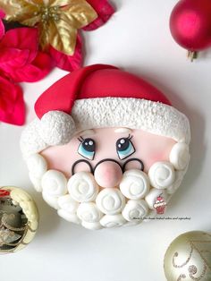 a close up of a santa clause face on a white surface with ornaments around it