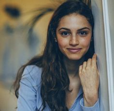 a woman leaning against a wall and smiling