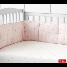 a white crib with pink and gold stars on it