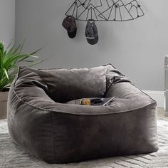 a grey bean bag chair sitting on top of a rug next to a potted plant