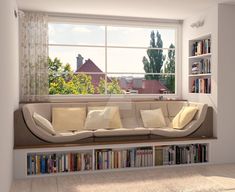 a couch sitting in front of a window next to a book shelf filled with books