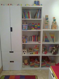 a white bookcase filled with lots of books next to a dresser and rug on the floor