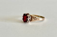 Beautiful antique circa 1800s Mid Victorian era 10k rosey gold created ruby ring! This stylish solitaire style ring features a oval faceted 1.25 carat created deep red gemstone. The stone is securely prong set in a crown style setting, with detailed shoulder work. A fantastic piece of fine mid Victorian era jewelry, featuring July's birthstone!  ERA - Circa 1861-1887 / Mid Victorian  METAL / MATERIAL - 10k rose gold, created ruby  (approx. 1.25CT)  [Synthetic ruby contains essentially the same c Victorian Rose Gold Ruby Ring, Antique Ruby Ring With Prong Setting, Antique 14k Gold Ruby Ring With Birthstone, Victorian 14k Gold Ruby Ring, Victorian 14k Gold Ruby Ring In Red, Victorian Ruby Ring In 14k Gold, Victorian Style 14k Gold Ruby Ring, Antique 14k Rose Gold Ruby Ring, Victorian Oval Ruby Ring