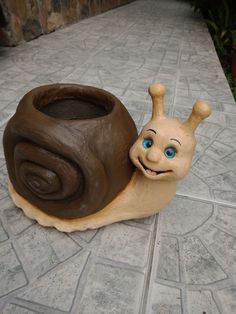 a snail statue sitting next to a clay pot