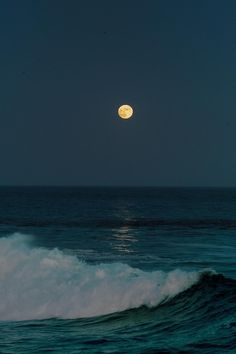 the moon is setting over the ocean waves