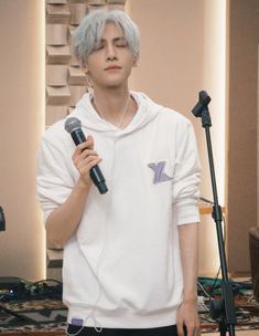 a young man holding a microphone in front of a recording studio