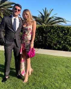 a man in a suit and tie standing next to a woman on the green grass