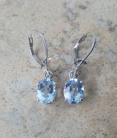 These beautiful stones are 8mm x 6mm genuine Aquamarine set in Sterling Silver handmade settings.The stones are about 1 carat each, total approx. 2 carats, and a very nice blue color.The settings are handmade by me and the Aquamarine dangle from lever backs which keep them safely in your ears.Aquamarine is the birthstone for March.These lovely Aquamarine drop earrings make a great gift for all ages. I can also sell just one piece, please convo me if interested.These are also available in Gold pl Classic Oval Sterling Silver Earrings, Classic Oval Earrings With Ear Wire, Formal Oval Pendant Gemstone Earrings, Classic Oval Cabochon Gemstone Earrings, Oval Ear Wire Earrings For Anniversary, Classic Oval Gemstone Earrings, Silver Oval Earrings, Aquamarine Earrings, Beautiful Stones