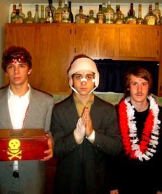 three men in costumes standing next to each other holding a box with a skull on it