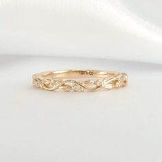 a gold wedding band with three diamonds on the bottom and an intricate design in the middle