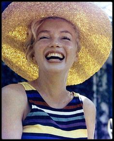 a smiling woman wearing a large straw hat