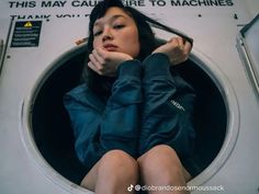 a woman is sitting in a washing machine