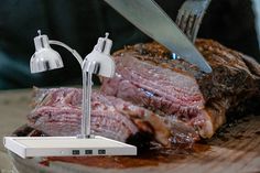 a steak being cut into pieces with a knife and fork on top of the meat