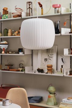 a white lamp hanging from the ceiling in a room filled with books and other items