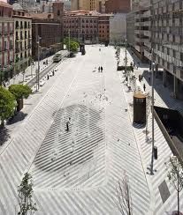 an aerial view of a city square with people walking around and buildings in the background