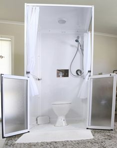 a white toilet sitting inside of a bathroom next to a shower head and door frame