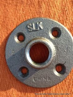 an old metal flange with holes in the center on a orange cloth background, closeup