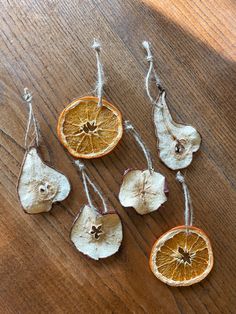 four dried oranges are hanging from twine on a wooden table with string attached to them