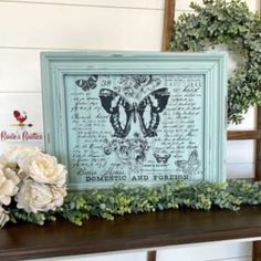 some flowers are sitting on a shelf next to a framed print with words and butterflies