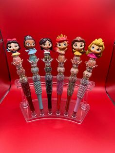 the disney princess figurines are lined up in a display case on a red background