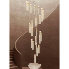 a modern chandelier hanging from the ceiling in front of a spiral stair case