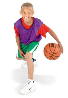 a young boy holding a basketball sitting on top of a white floor