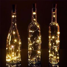 three bottles with lights in them sitting on a table