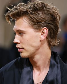 a close up of a person wearing a black shirt and tie with his hair blowing in the wind