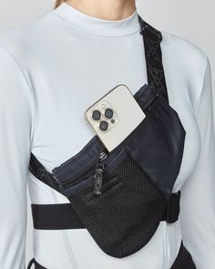 a woman wearing a white shirt and black suspenders with an iphone in her back pocket