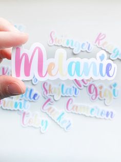 someone holding up a sticker with the word melanie written in multicolored letters