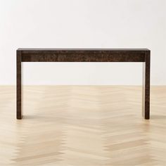 a wooden table sitting on top of a hard wood floor next to a white wall