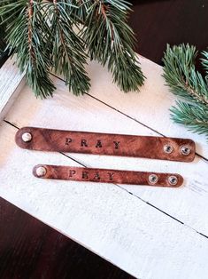 two personalized wooden spoons sitting on top of a table next to pine branches