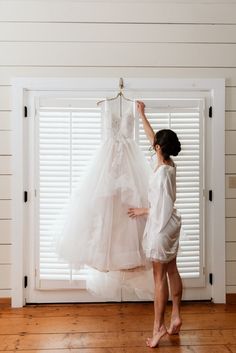 a woman is trying to hang her wedding dress