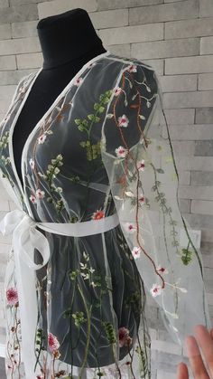 a dress with flowers on it is being held up by a mannequin's torso