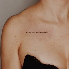 a woman wearing a face mask with the words i am enough tattooed on her chest